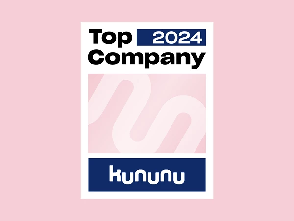 Das Bild zeigt ein Emblem mit der Aufschrift "Top Company 2024" in schwarzer und blauer Schrift auf einem rosa Hintergrund. Unten befindet sich das Wort "kununu" in blauer Schrift.