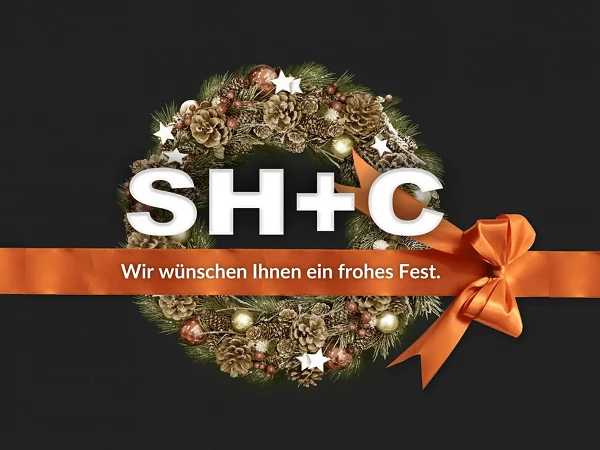 Ein festlicher Kranz aus Tannenzweigen, Tannenzapfen und goldenen Weihnachtskugeln mit einem orangefarbenen Schleifenband, vor einem dunklen Hintergrund. Im Zentrum steht der Schriftzug „SH+C“ und darunter der Text „Wir wünschen Ihnen ein frohes Fest.“
